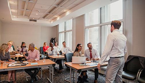 Employees at desks with instructor teaching