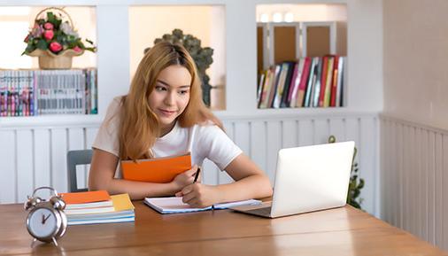 Young woman student working on laptop sitting at a desk